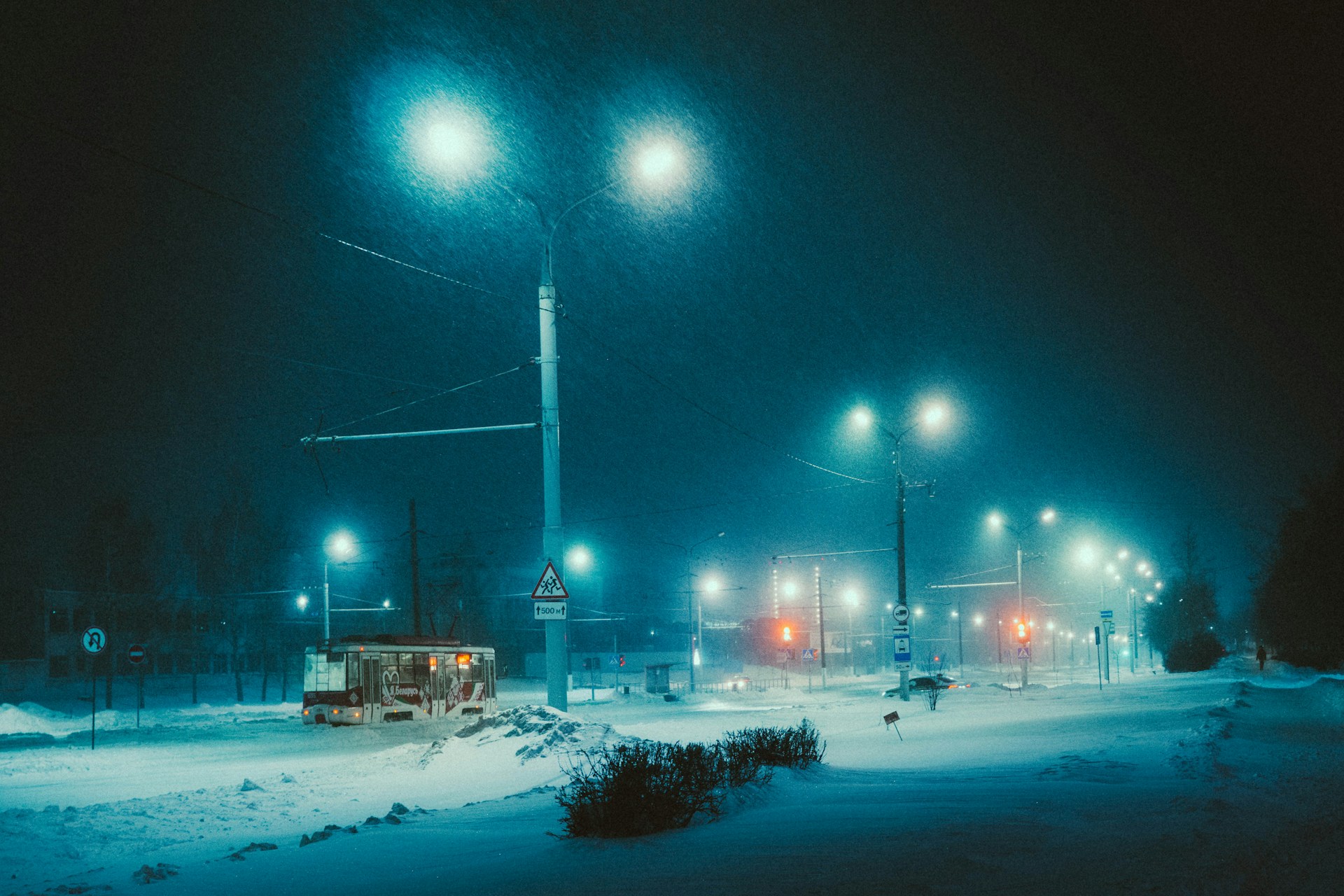 Una foto notturna, paesaggio innevato con tram solitario che passa