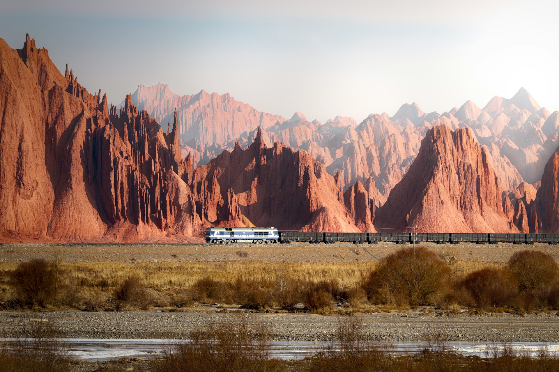 Un treno passa in un paesaggio brullo con montagne
